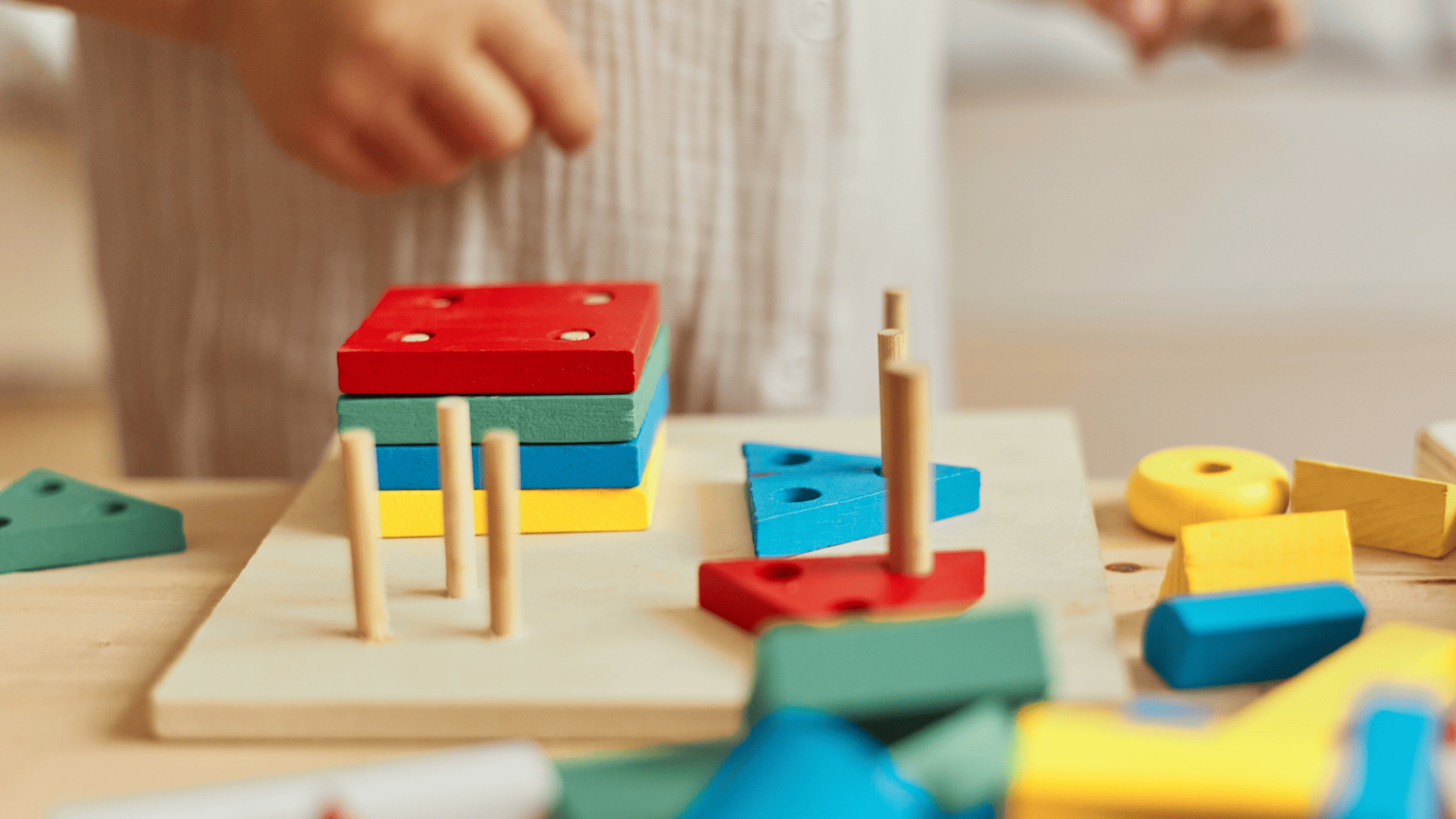Close up of child's hands playing with coloured wooden toys